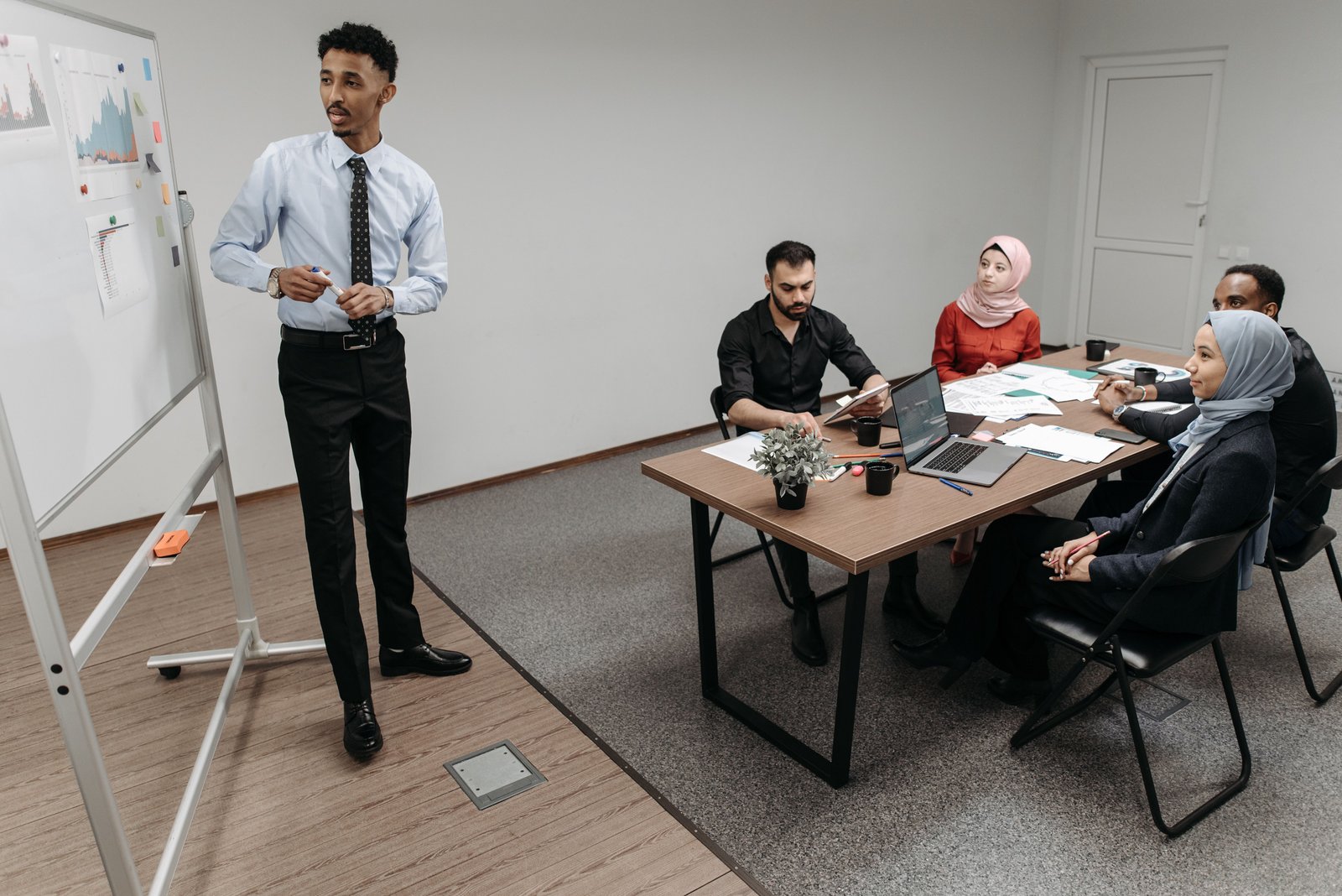 A presenter reviewing charts with colleagues, evoking a CIO briefing a board on technical debt