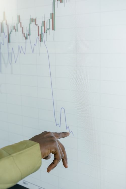 A hand pointing to a declining trend line on a screen, representing shrinking CRM budgets amid the enrollment cliff